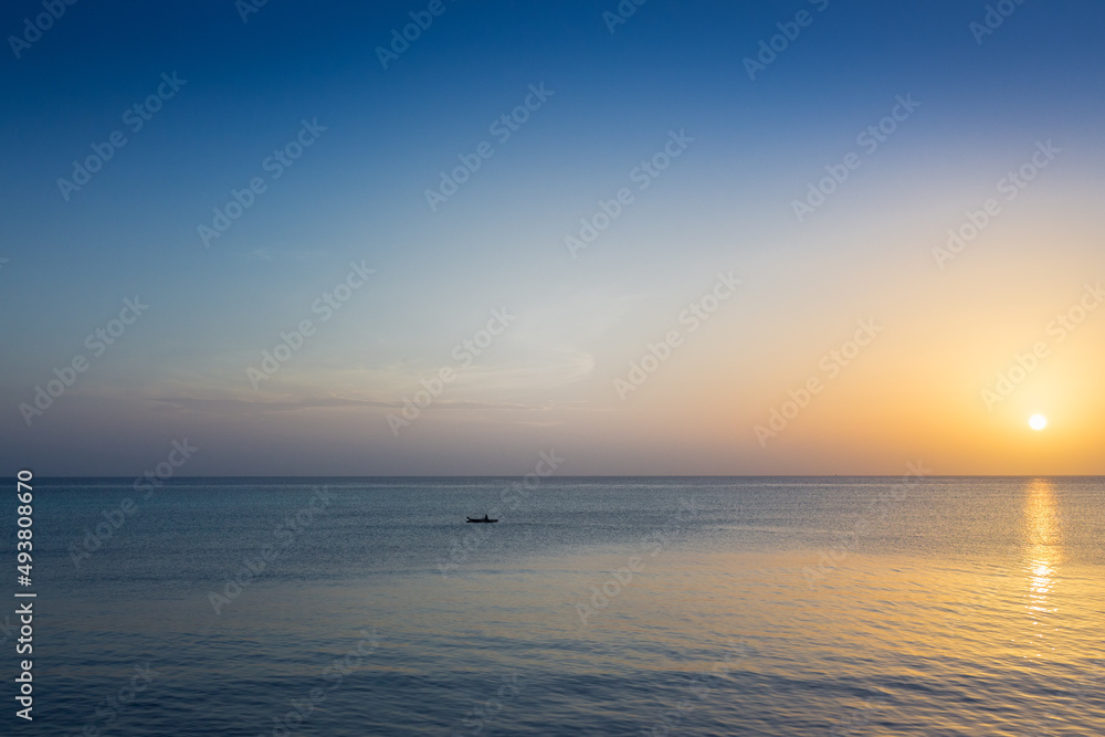 Obraz premium Boat at picturesque sunset. Aerial ambient seascape. Peaceful seascape with sailing boat and copy space. Colorful evening sky over tranquil ocean. Golden sunset at the beach. Tropical vacations. 