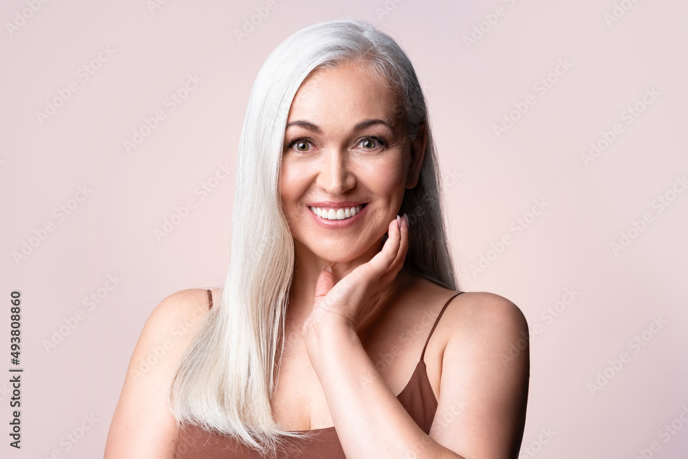Gray-haired woman looking at camera. Positive single mature senior retired woman touching healthy groomed perfect face skin. Natural old beauty and aging concept. Gray-haired woman looking at camera. Positive single mature senior retired woman touching healthy groomed perfect face skin. Natural old beauty and aging concept.