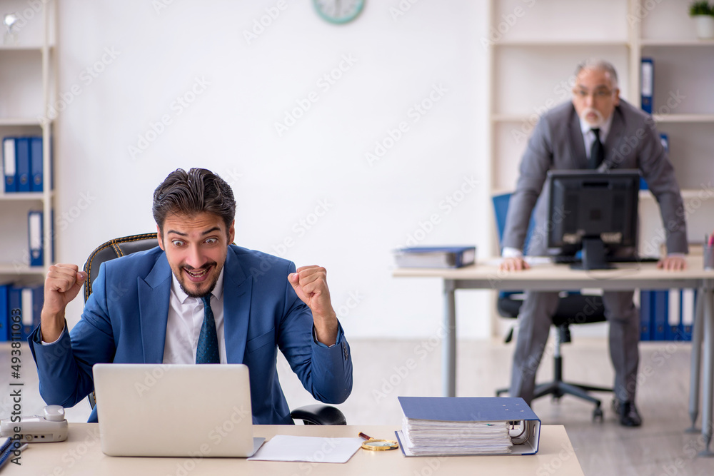 Old male boss and young male employee working in the office