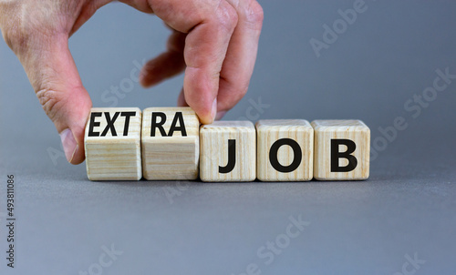 Extra job symbol. Businessman turns wooden cubes and changes concept words Job to Extra job. Beautiful grey table grey background, copy space. Business extra job concept.