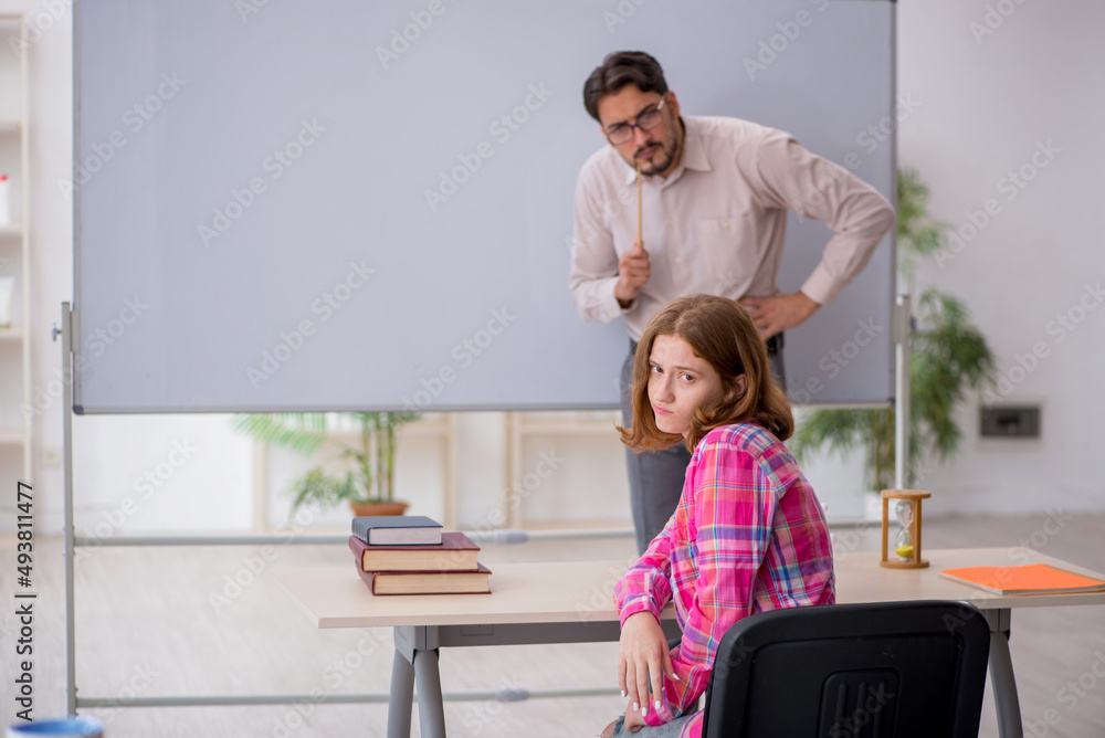 Young male teacher and redhead girl in the classroom Young male teacher and redhead girl in the classroom