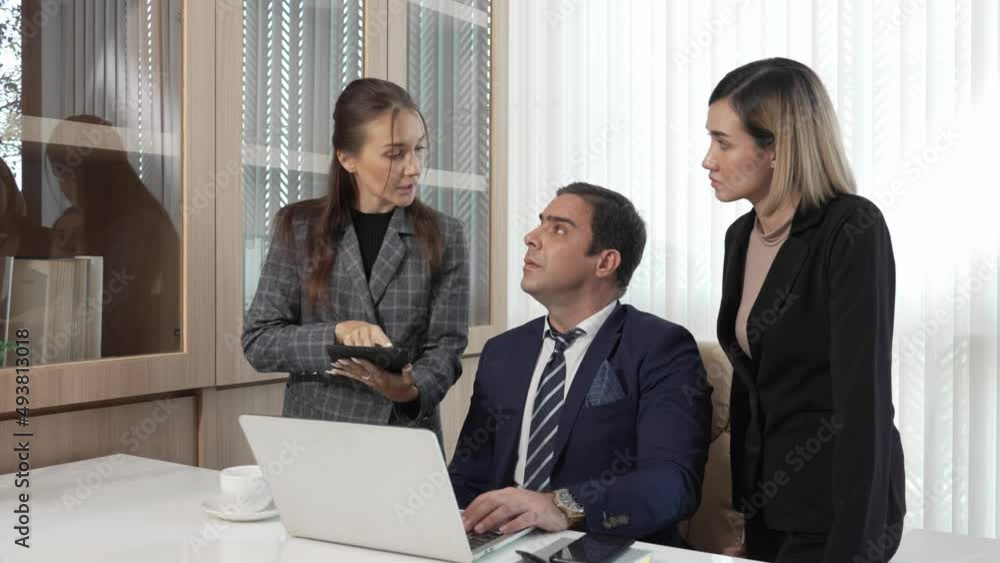 Business team discussing checking workflows in the office, female hands shows electronic documents in tablet to her boss and pointing on the screen of tablet while working on desk with laptop. Business team discussing checking workflows in the office, female hands shows electronic documents in tablet to her boss and pointing on the screen of tablet while working on desk with laptop.