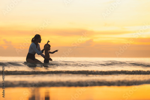 Happy family resting at beach in summer, Mother and baby boy feet at the sea foam at the sunlight water is moving © grooveriderz