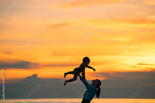 Happy family resting at beach in summer  Mother and baby boy feet at the sea foam at the sunlight water is moving