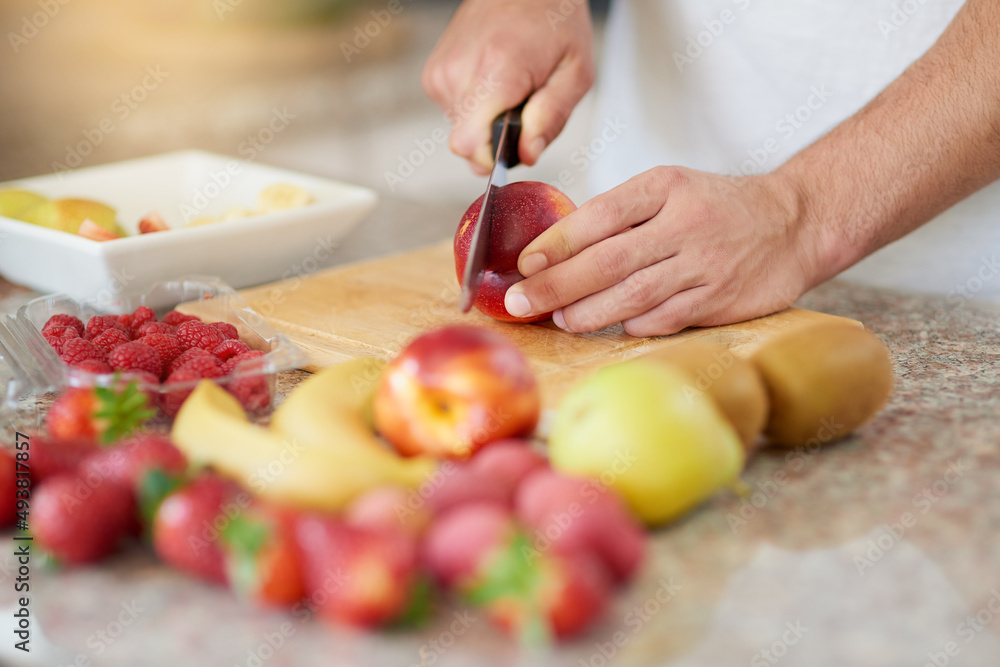 Have yourself a fruity day. Cropped shot of a young man making a fruit salad in his kitchen. Have yourself a fruity day. Cropped shot of a young man making a fruit salad in his kitchen.