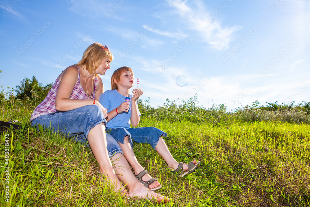 mother and son blowing bubbles outdoors