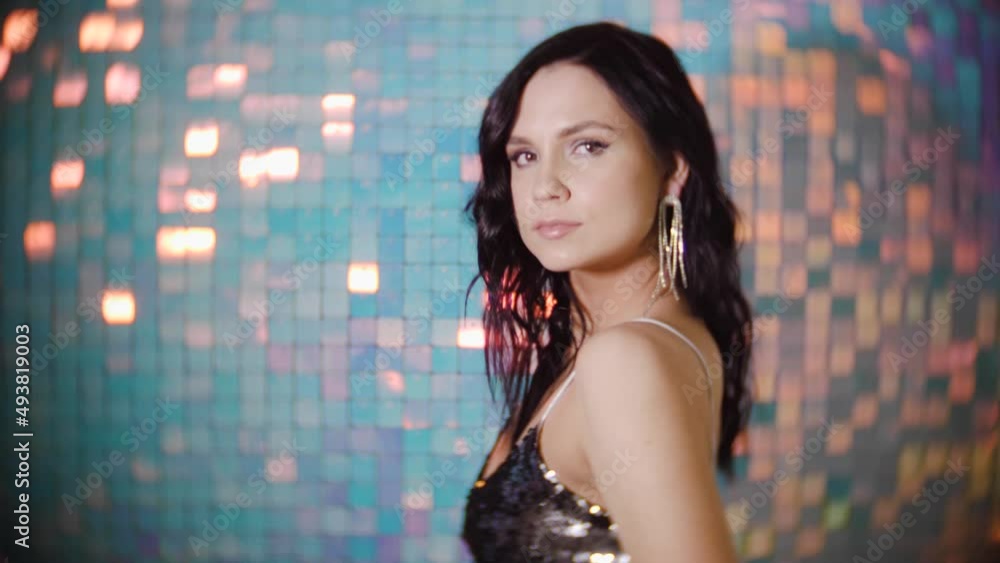 portrait of a sexy brunette woman with earrings and a silver top on a shiny background in the studio portrait of a sexy brunette woman with earrings and a silver top on a shiny background in the studio