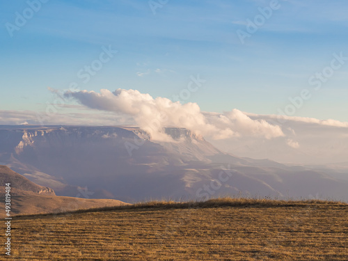 Fototapeta Naklejka Na Ścianę i Meble -  Clouds float on a plateau located in the distance in the mountain valley of the Caucasus