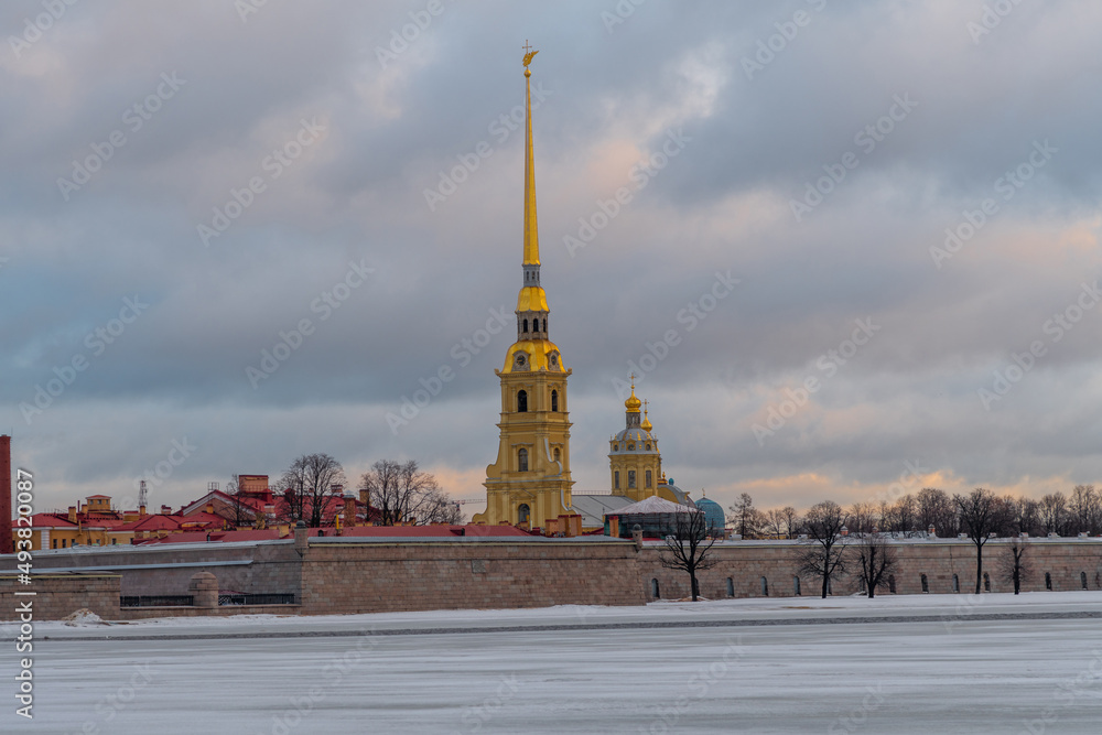 Saints Peter and Paul Cathedral in Peter and Paul Fortress in the early morning in Saint Petersburg city, Russia. Neva river covered with ice. Cloudy sky. Travel in Russia theme.