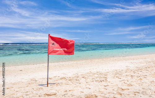 Red flag warning on sandy beach