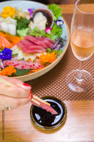 Woman eating delicious sashimi, closeup on chopsticks.