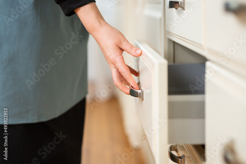 Close-up of a woman's hand closing a kitchen table drawer. Selective soft focus