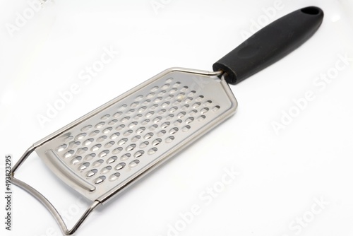 Metal grater for cheese and other kitchen ingredients on white background with copy space photo