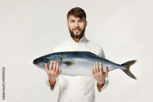  the chef holds in his hands a big tuna on a white isolated background
