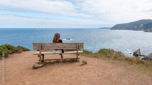 Little girl on the famous Loiba bench in Punta Estaca de Bares in Galicia, Spain