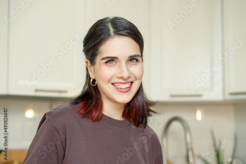 Portrait of young happy smiling brunette woman in cozy home kitchen