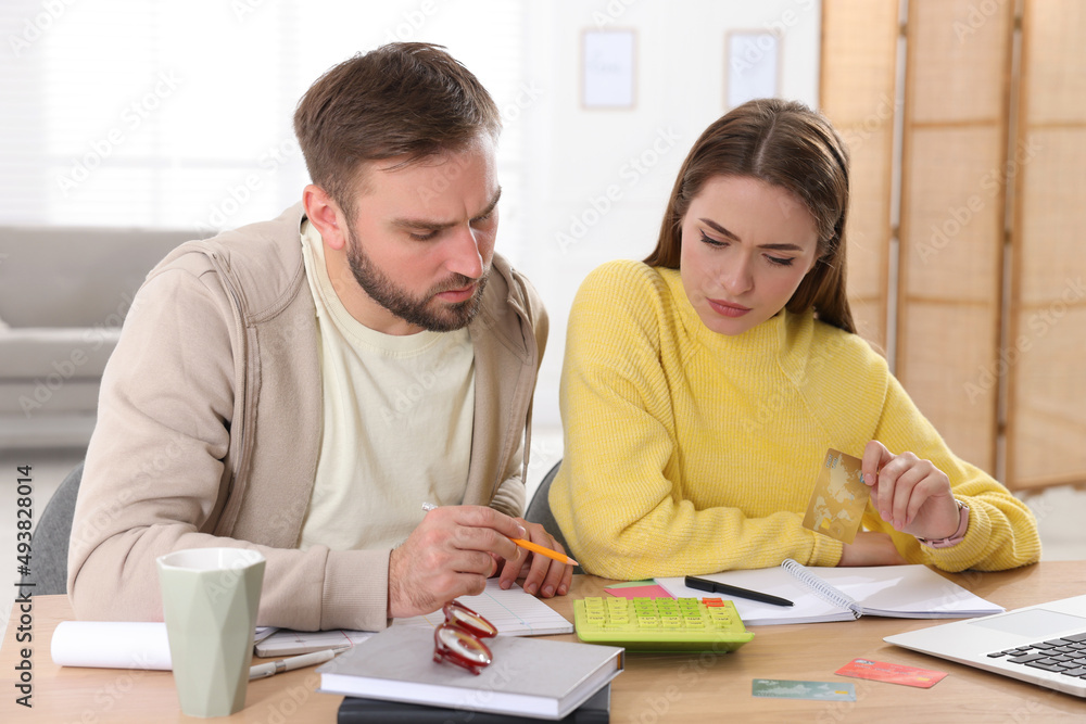 Young couple discussing family budget at table in living room Young couple discussing family budget at table in living room