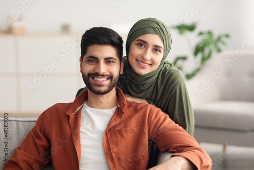 Middle Eastern Spouses Hugging Looking At Camera Sitting At Home