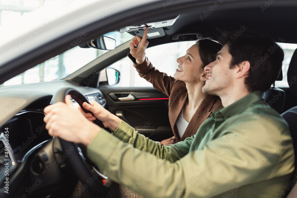 Happy millennial couple test driving new car at automobile dealership Happy millennial couple test driving new car at automobile dealership