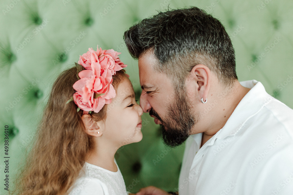 Happy hispanic dad and daughter. Green background, studio shot. Fatherhood and father day concept Happy hispanic dad and daughter. Green background, studio shot. Fatherhood and father day concept