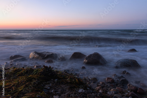 Smooth water with rocks and stranded sea grass at the swash zone. 