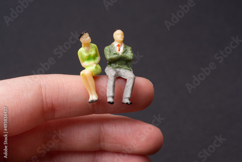 Tiny figurine of man and woman models sitting on a finger photo