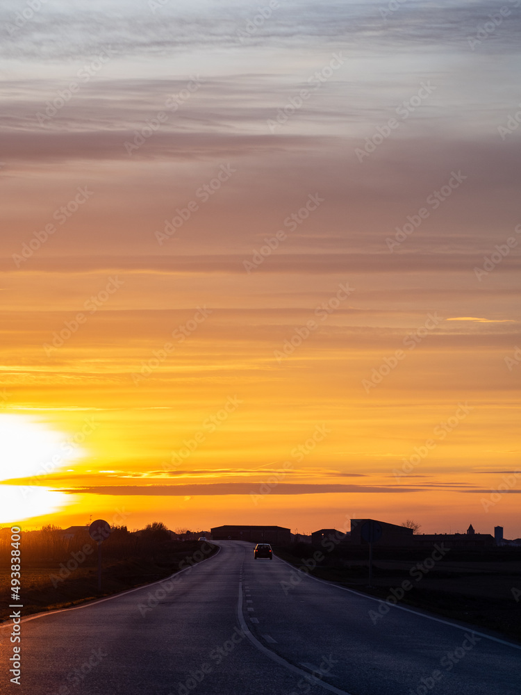 Beautiful sunset over asphalt road with car in the distance