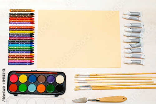 Watercolor oil paints, paintbrushes, colorful pencils, pastel crayons,blank watercolor paper pad. Creativity creation process. Artist's stuff on white table.Top view Flatlay of drawing supplies