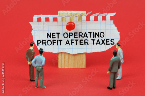 On a red background are miniature figures of people looking at an ad with the inscription Net Operating Profit After Tax photo