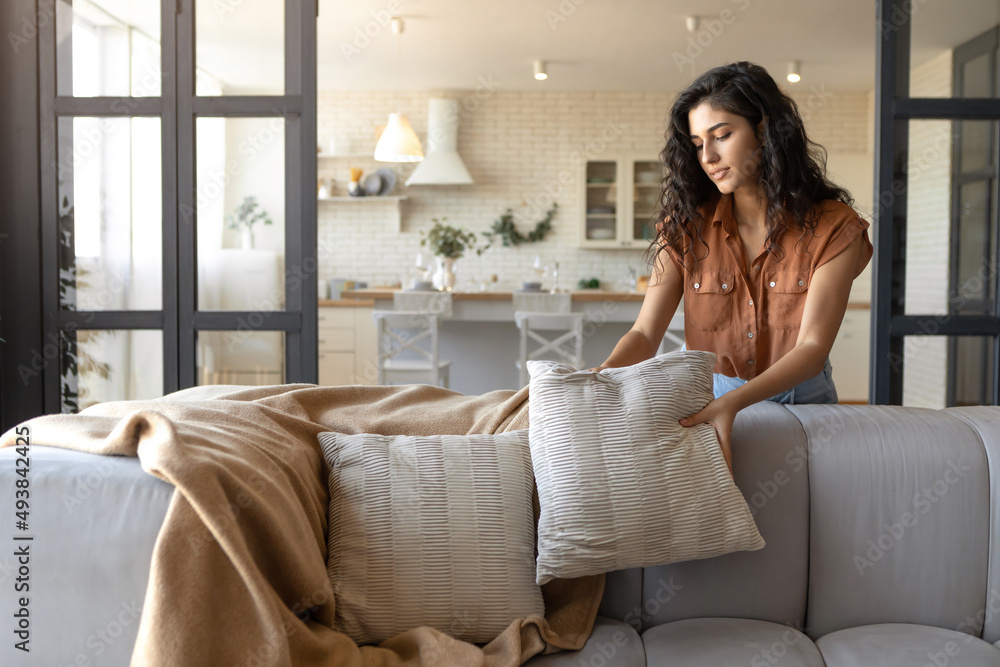 © Prostock-studio - Attractive young woman arranging pillows and plaid on comfortable sofa, making her home cozy, empty space © Prostock-studio - Attractive young woman arranging pillows and plaid on comfortable sofa, making her home cozy, empty space