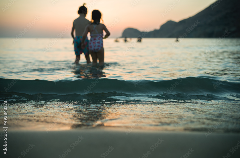 Fototapeta premium eautiful beach, a shining sun, and laughing children — what else could you possibly want from a sunset