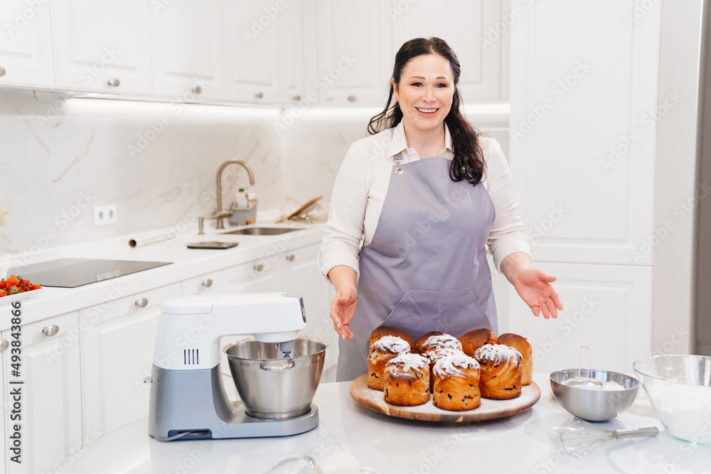 female cook with Kraffins, easter cakes and Panettones in the kitchen. female cook with Kraffins, easter cakes and Panettones in the kitchen.