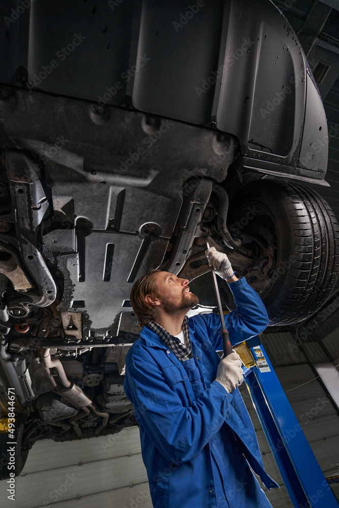 Male working at service station and repairing car