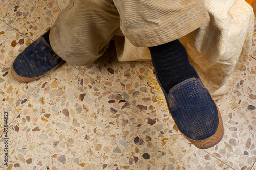 zapatillas sencillas de persona mayor sobre racholas de piedras clásica y pantalon de pana vintage photo