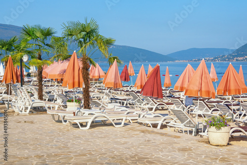 Summer beach vacation. Sunny Mediterranean landscape with beach umbrellas. Montenegro, Adriatic Sea, Bay of Kotor near Tivat city