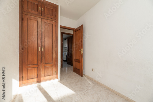 Empty room with light stoneware floor  two-body built-in wardrobe with trunk and door of the same color