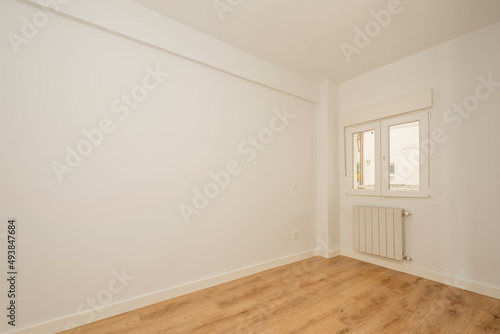 empty room with chestnut wood parquet and freshly painted walls and white aluminum radiator