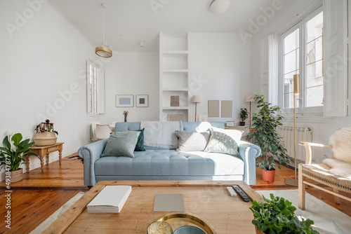 Photos Living room with a blue three-seater sofa, wooden tables and decorative indoor p