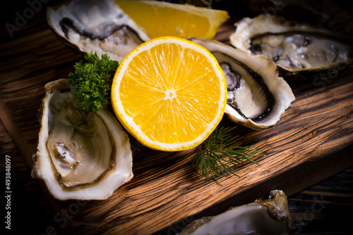 fresh oysters, lemon on wooden background