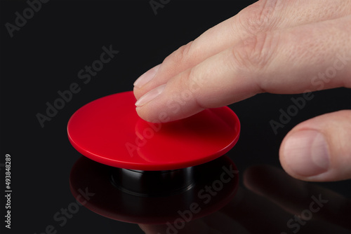 The hand presses the big red button. The concept of the threat of nuclear war. A threat to the world with a nuclear suitcase and a bomb. The hand presses the rocket launch button.