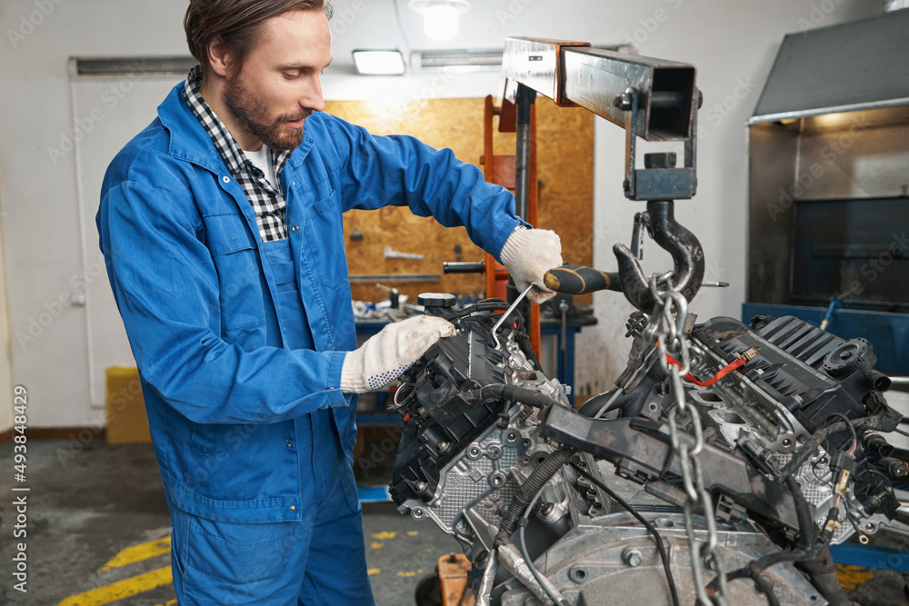 Man is inspecting auto detail during repair Man is inspecting auto detail during repair