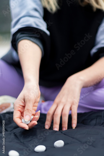 Girl playing five stones game. Her face is not seem in photo. Unrecognizable person. The focus is on her hand. Flu background. 