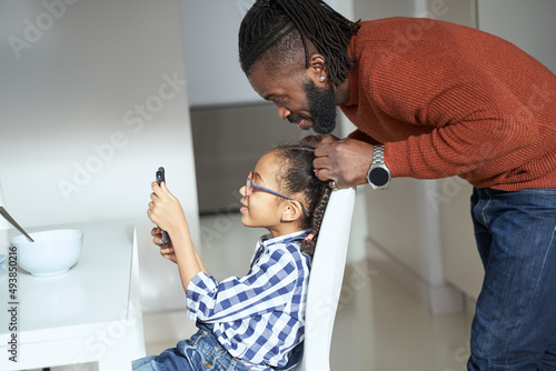 Joyous bearded man watching at smartphone with his young dauther