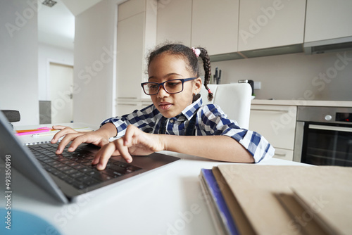 Little girl working carefully on her laptop