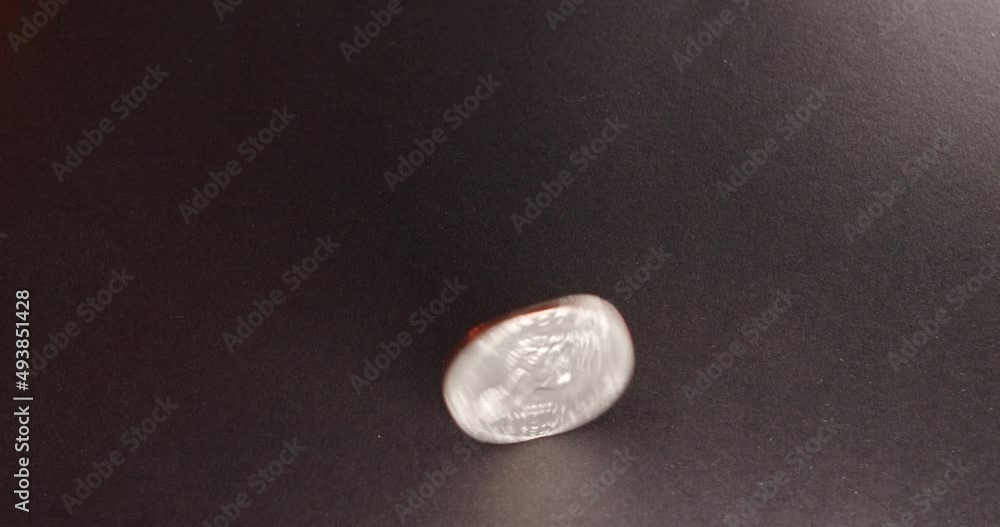 One Dollar coin, Eisenhower Dollar spinning on dark surface. Rotating, one Dollar coin One Dollar coin, Eisenhower Dollar spinning on dark surface. Rotating, one Dollar coin
