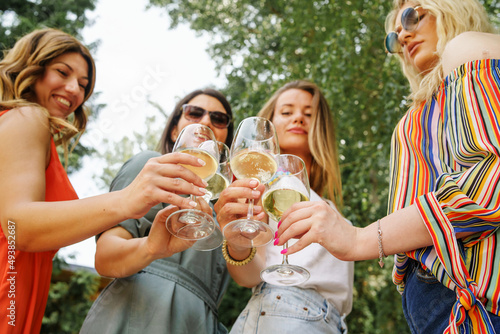 Close up on hands of unknown caucasian women holding glasses of white wine toasting and celebrating while standing outdoor