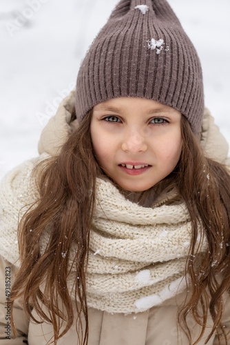 large portrait of a cute blonde girl in a warm hat in winter