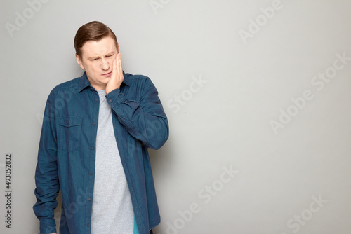 Portrait of unhappy man touching cheek and suffering from toothache photo