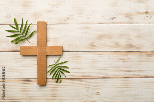 Palm branches and cross on wooden background, top view. Palm Sunday concept