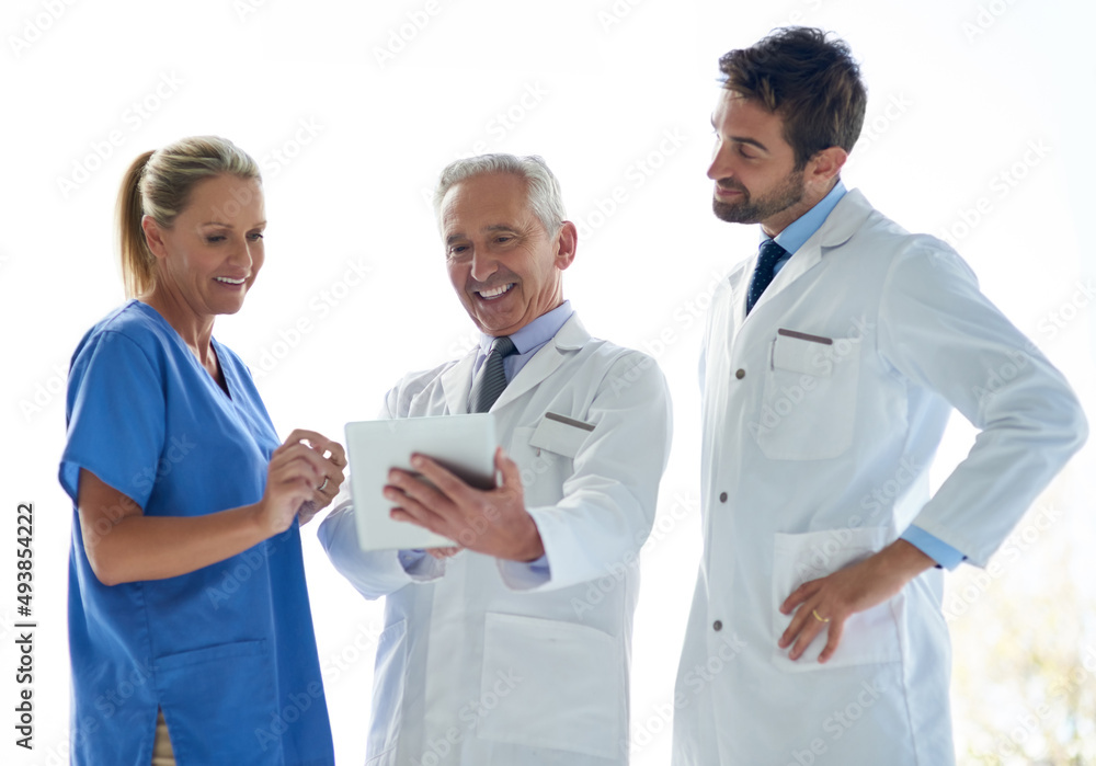 Working together to help keep you well. Cropped shot of a group of medical practitioners discussing something on a digital tablet together. Working together to help keep you well. Cropped shot of a group of medical practitioners discussing something on a digital tablet together.